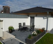  Terrasse hinter dem Haus mit Sonnenschirm und Grill